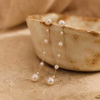 Long gold-tone drop earrings featuring natural freshwater pearls; minimalist-style 18K gold-plated earrings