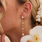 Long gold-tone drop earrings featuring natural freshwater pearls; minimalist-style 18K gold-plated earrings